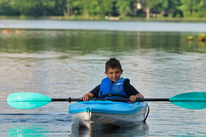 A boy grinning in a kayak on the lake