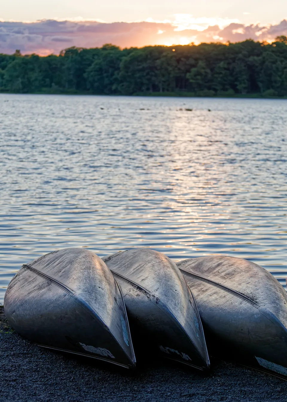 Three canoes on the shore at sunset