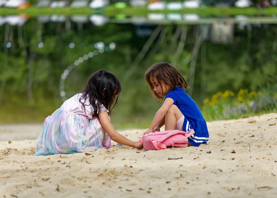 Two little girls playing in the sand at the beach